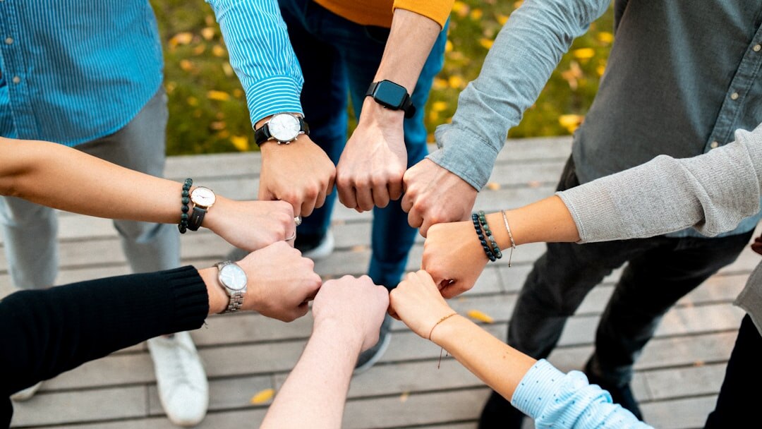 Diverse group of colleagues holding hands in a circle during an outdoor team building activity